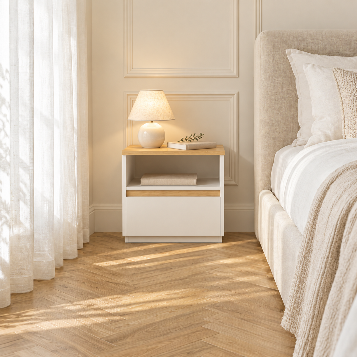 Même chambre aménagée avec un chevet blanc et bois, une lampe en céramique et des livres.