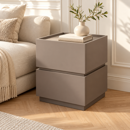 Deux modules gris taupe empilés près d’un canapé crème, avec des livres et un vase sur le plateau supérieur.