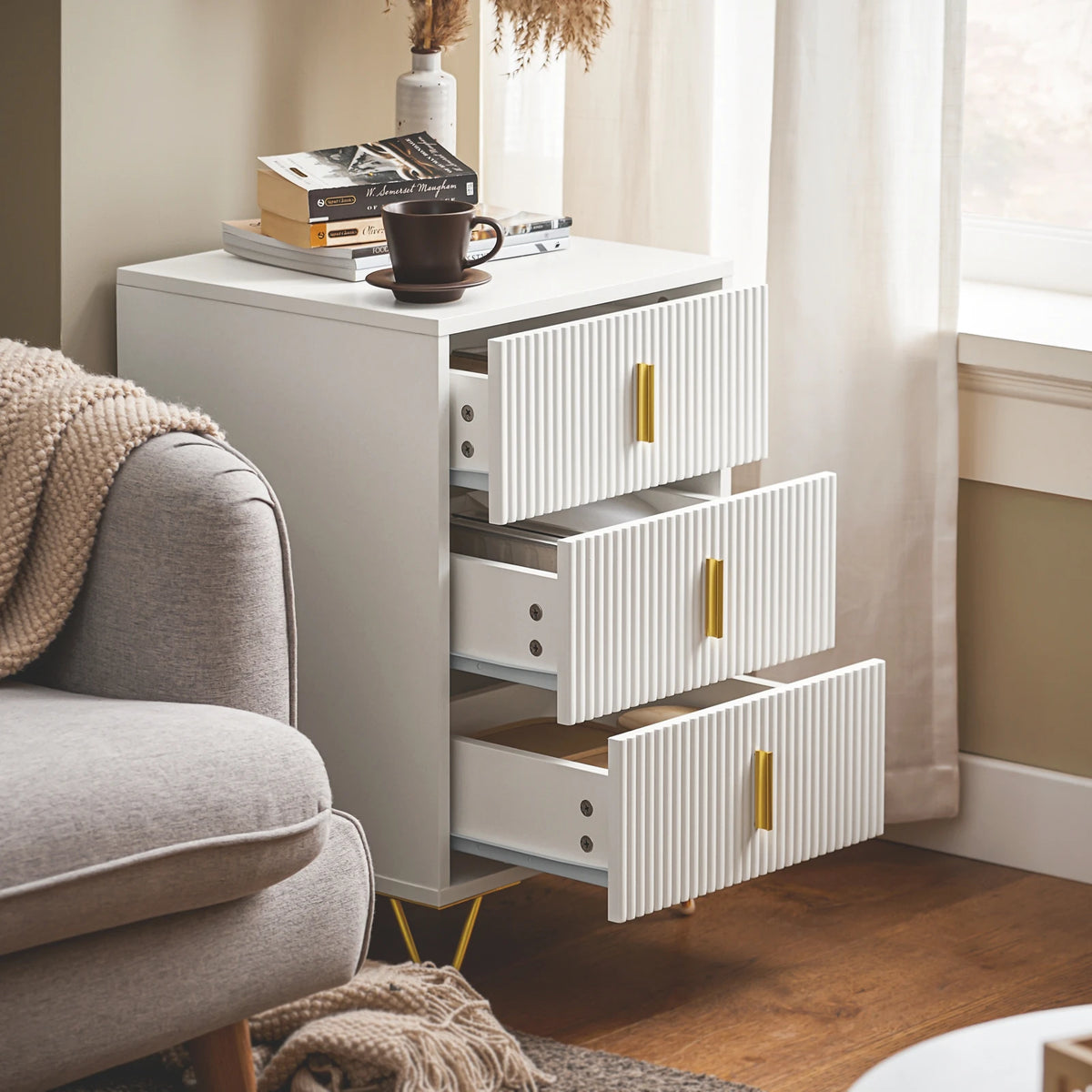 table de chevet blanche avec 3 tiroirs ouverts dans un salon design