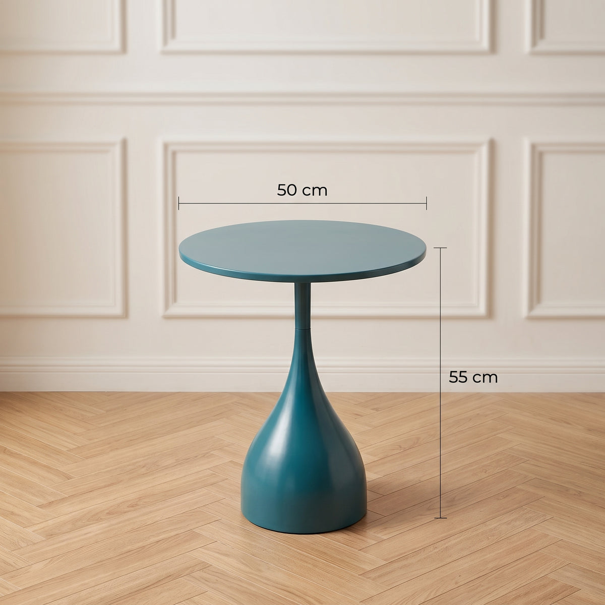 Une photo de studio carrée de style magazine de décoration montrant la table d'appoint tulip-base bleu pétrole. Des lignes de mesure et des étiquettes en français sont superposées : '50 cm' pour le diamètre du plateau, et '55 cm' pour la hauteur totale du sol au plateau. Le fond est un mur de moulures subtilement flouté