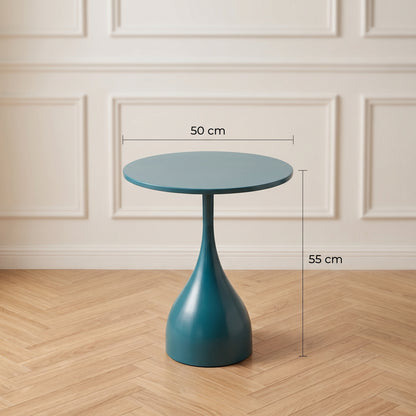 Une photo de studio carrée de style magazine de décoration montrant la table d'appoint tulip-base bleu pétrole. Des lignes de mesure et des étiquettes en français sont superposées : '50 cm' pour le diamètre du plateau, et '55 cm' pour la hauteur totale du sol au plateau. Le fond est un mur de moulures subtilement flouté