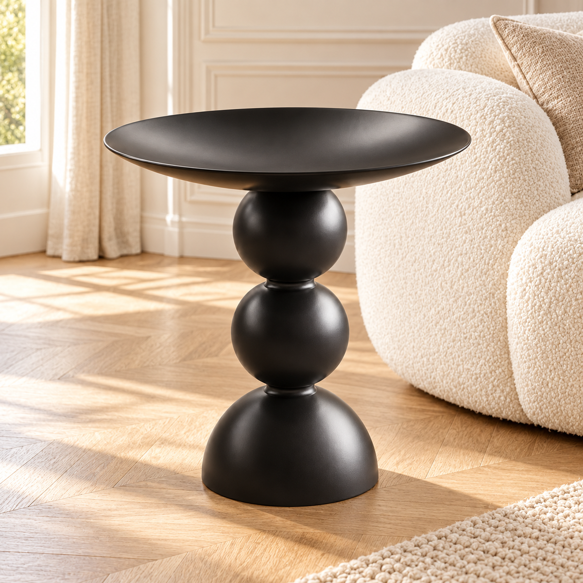 Table d’appoint noire au plateau en cuvette près d’un canapé écru dans un salon lumineux avec moulures
