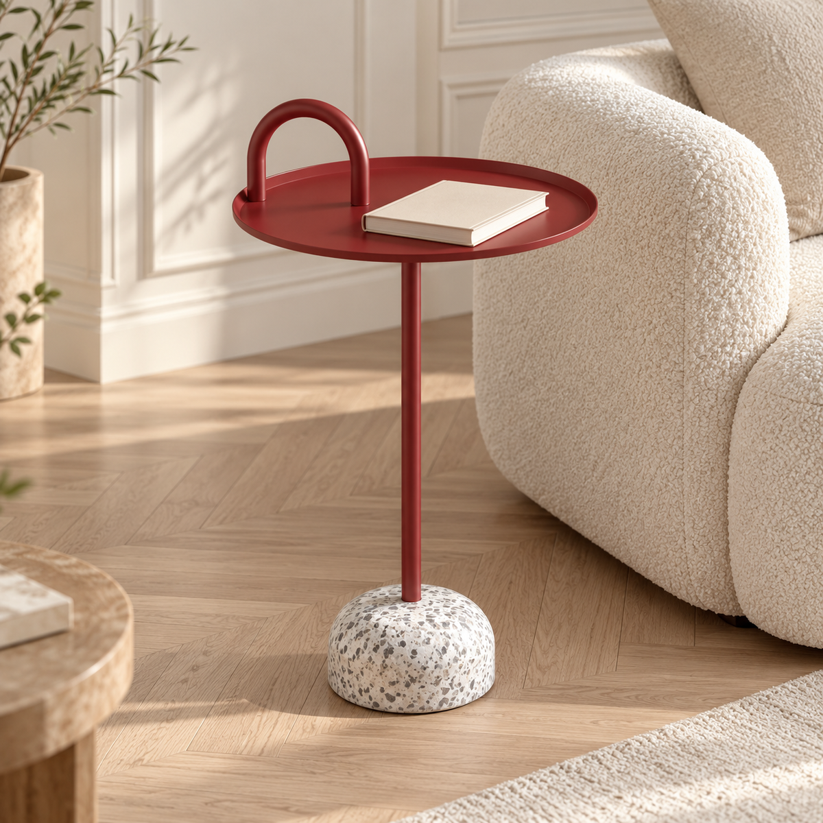 Table d’appoint rouge avec un livre sur son plateau près d’un canapé écru dans un salon lumineux