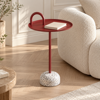 Table d’appoint rouge avec un livre sur son plateau près d’un canapé écru dans un salon lumineux