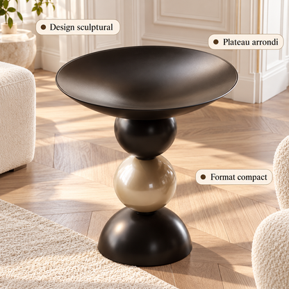 Table d’appoint noire et dorée présentant son design sculptural, son plateau arrondi et son format compact