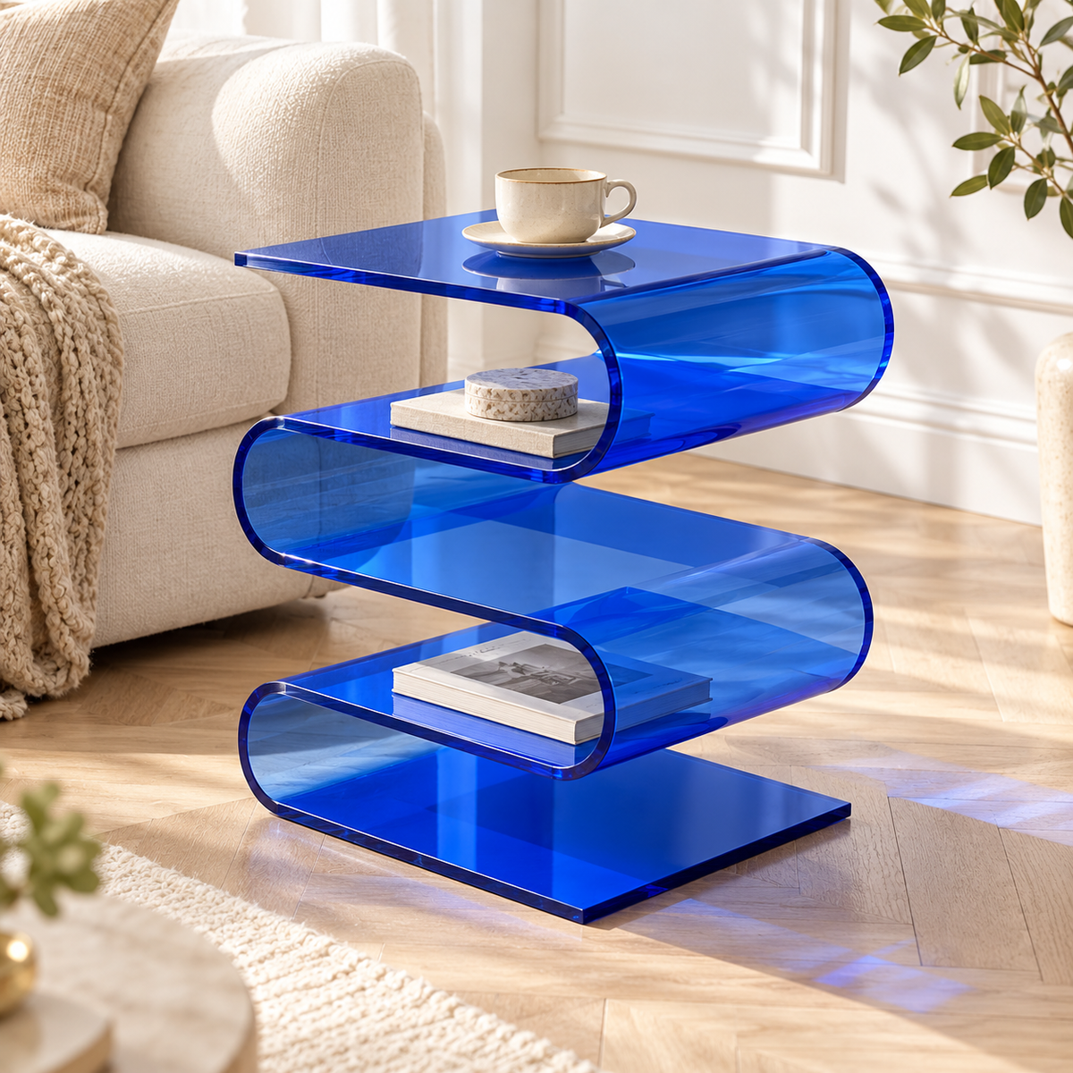Table d’appoint bleue en forme de vague près d’un canapé écru, avec tasse et livres